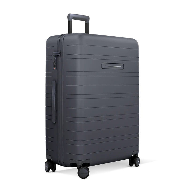 Horizn Studios H7 RE dark slate check-in suitcase with four wheels and ergonomic handle, designed for easy travel.